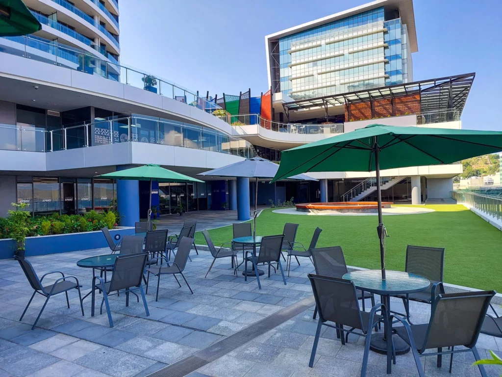 View of exterior tables and chairs with umbrellas leading out to lawn area at Commercial Plaza